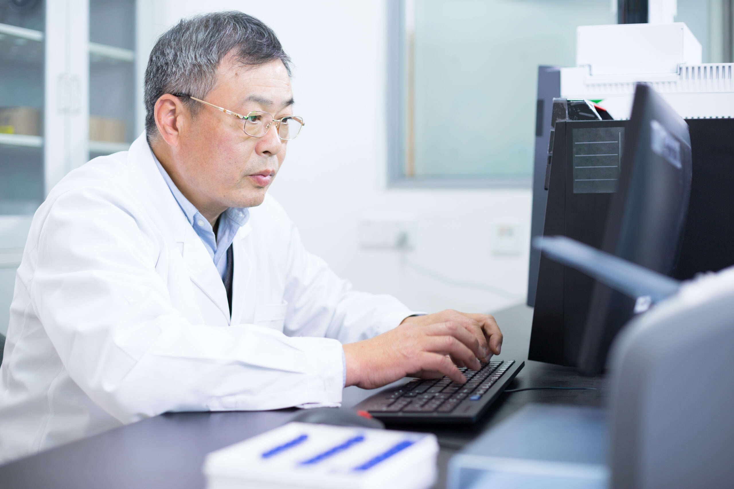 Asian old man nalysises chemical experimental data in computer in lab